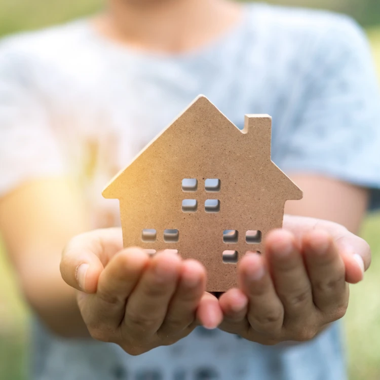 Holding a cardboard house with hands.